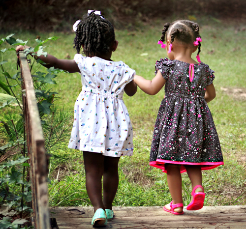 two little girls holding hands walking